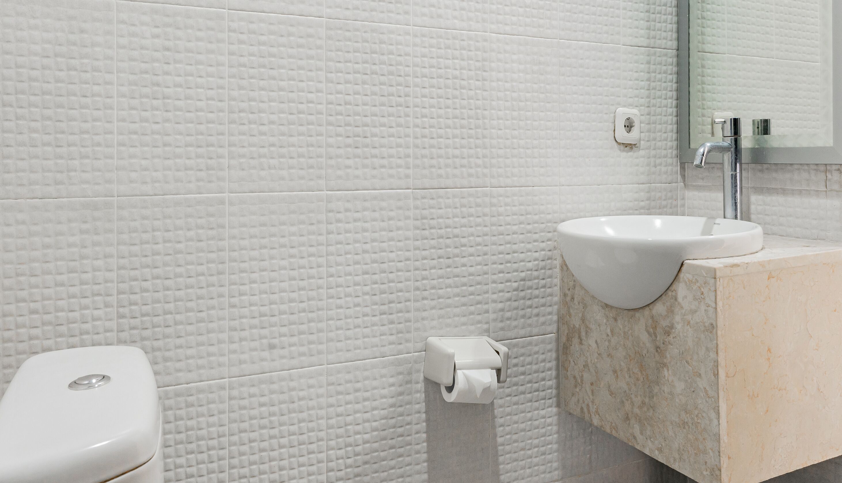 A bathroom with a white sink, a toilet, and a mirror.