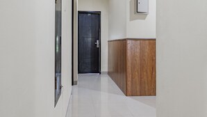 A hallway with a door marked '209', a wooden panel, and a light switch on the wall. - Collection O Kuta Near Airport Ngurah Rai (Tuban)