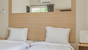A hotel room with two beds, a large mirror, and a wooden headboard. - Collection O Kuta Near Airport Ngurah Rai (Tuban)