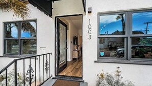 A modern house with a number 1003 on the wall, a wooden interior, and a black metal staircase. - Dahlia Suite I Steps to Bay, Shops, Food + More (Coronado)