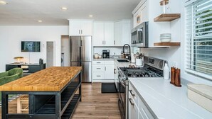 Una cocina moderna con armarios blancos, electrodomésticos de acero inoxidable y una mesa de comedor de madera.