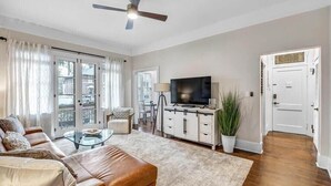 A modern living room with a leather sofa, glass coffee table, and a flat-screen TV on a cabinet.
