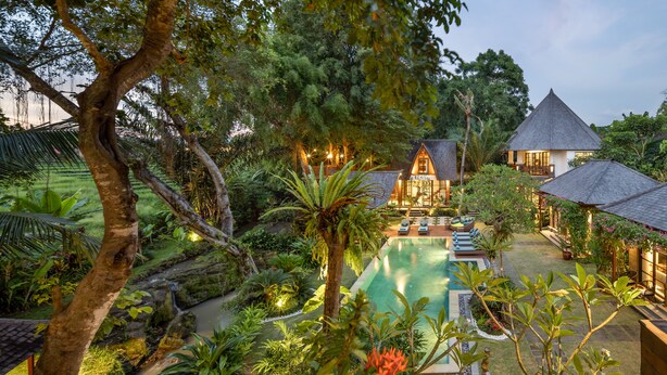 Un complexe hôtelier tropical doté d’une piscine, d’une végétation luxuriante et de bâtiments de style traditionnel.