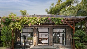 Une maison moderne dotée d’un patio couvert, de grandes fenêtres et d’un jardin.