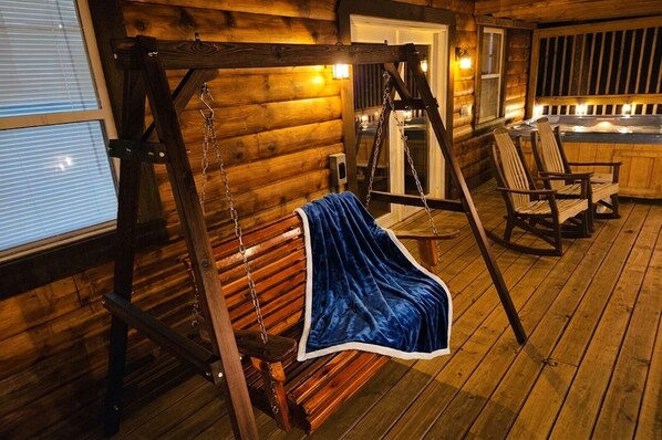 L’intérieur d’un chalet en bois est aménagé avec un fauteuil suspendu, une terrasse en bois et un espace équipé d’un bain à remous.