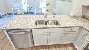 A kitchen with a granite countertop, stainless steel sink, and white cabinetry. - New Cozy SanDestin Beach TownHome/30A (Santa Rosa Beach)