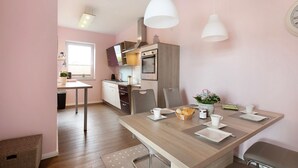 Een moderne keuken met een eethoek, houten vloer en hanglampen.