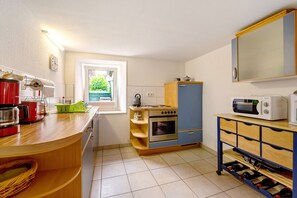 A compact kitchen with a stove, oven, microwave, and a wine rack. - Holiday Home 'Haus Gertrud' with Mountain View, Private Terrace and Wi-Fi (Monzelfeld)