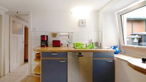 A compact kitchen with a dishwasher, a red coffee maker, and a window with a view of the outside. - Holiday Home 'Haus Gertrud' with Mountain View, Private Terrace and Wi-Fi (Monzelfeld)
