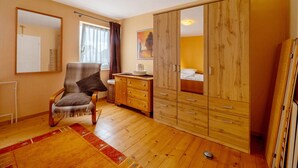 A room with wooden flooring, a chair, a wardrobe, and a bed. - Holiday Home 'Haus Gertrud' with Mountain View, Private Terrace and Wi-Fi (Monzelfeld)