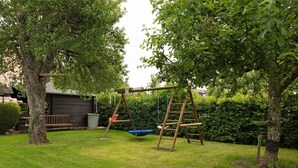 A backyard with a swing set, a wooden bench, and a shed. - Holiday Home 'Haus Gertrud' with Mountain View, Private Terrace and Wi-Fi (Monzelfeld)