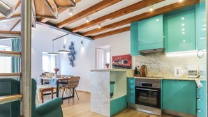 A modern kitchen with teal cabinets, a marble countertop, and a built-in oven. - Vita Portucale Setubal Deluxe Apartment (Setúbal)