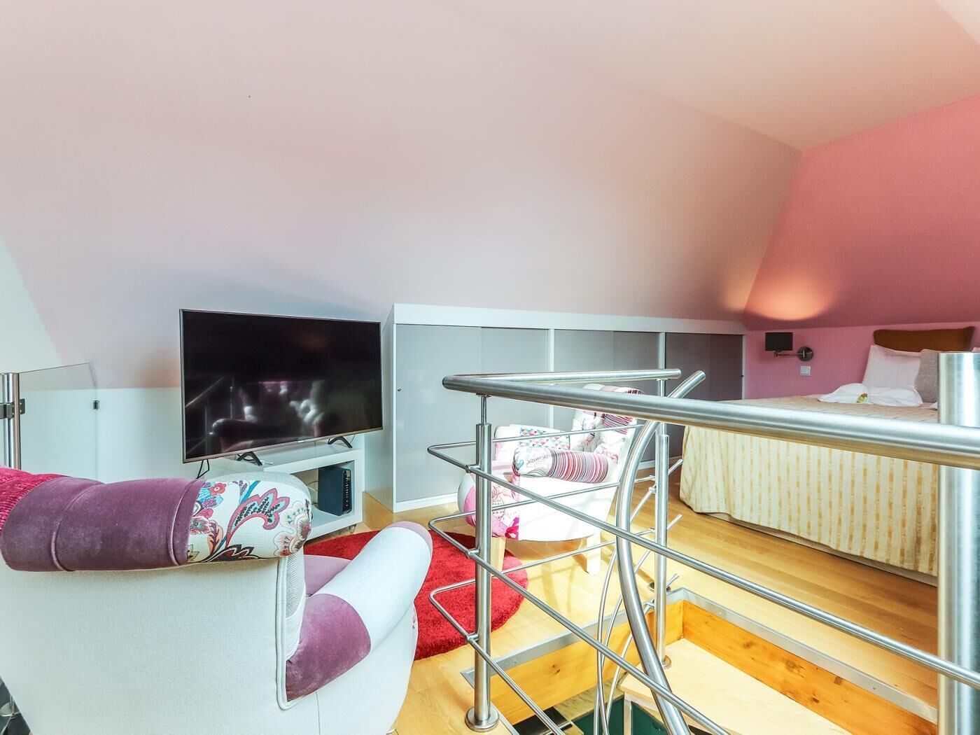 A compact hotel room with a bed, a TV, a chair, and a small table.