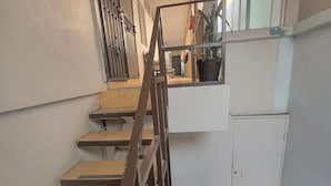 Eine Treppe mit Metallgeländer, die zu einem Zwischenpodest mit einem Topfpflanzen führt.