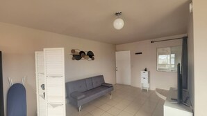 Ein geräumiger Wohnbereich mit einem grauen Sofa, einem weißen Schrank und einer Wanddekoration.