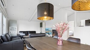 Un salon moderne avec une table à manger en bois foncé, des canapés en cuir noir et un vase rempli de fleurs.
