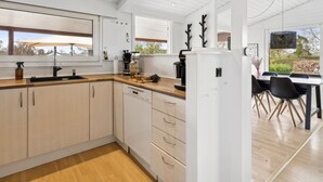 Une cuisine moderne avec des meubles en bois, un lave-vaisselle encastré et un coin repas comprenant une table et des chaises.