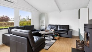 Un salon moderne avec un canapé en cuir noir, une table basse ronde et une cheminée.