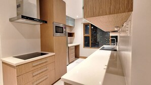 Een moderne keuken met een ingebouwde magnetron, een roestvrijstalen afzuigkap en een raam met uitzicht op de stad.
