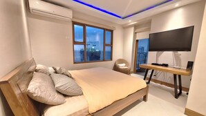 Een moderne slaapkamer met een groot bed, een televisie en uitzicht over de stad.