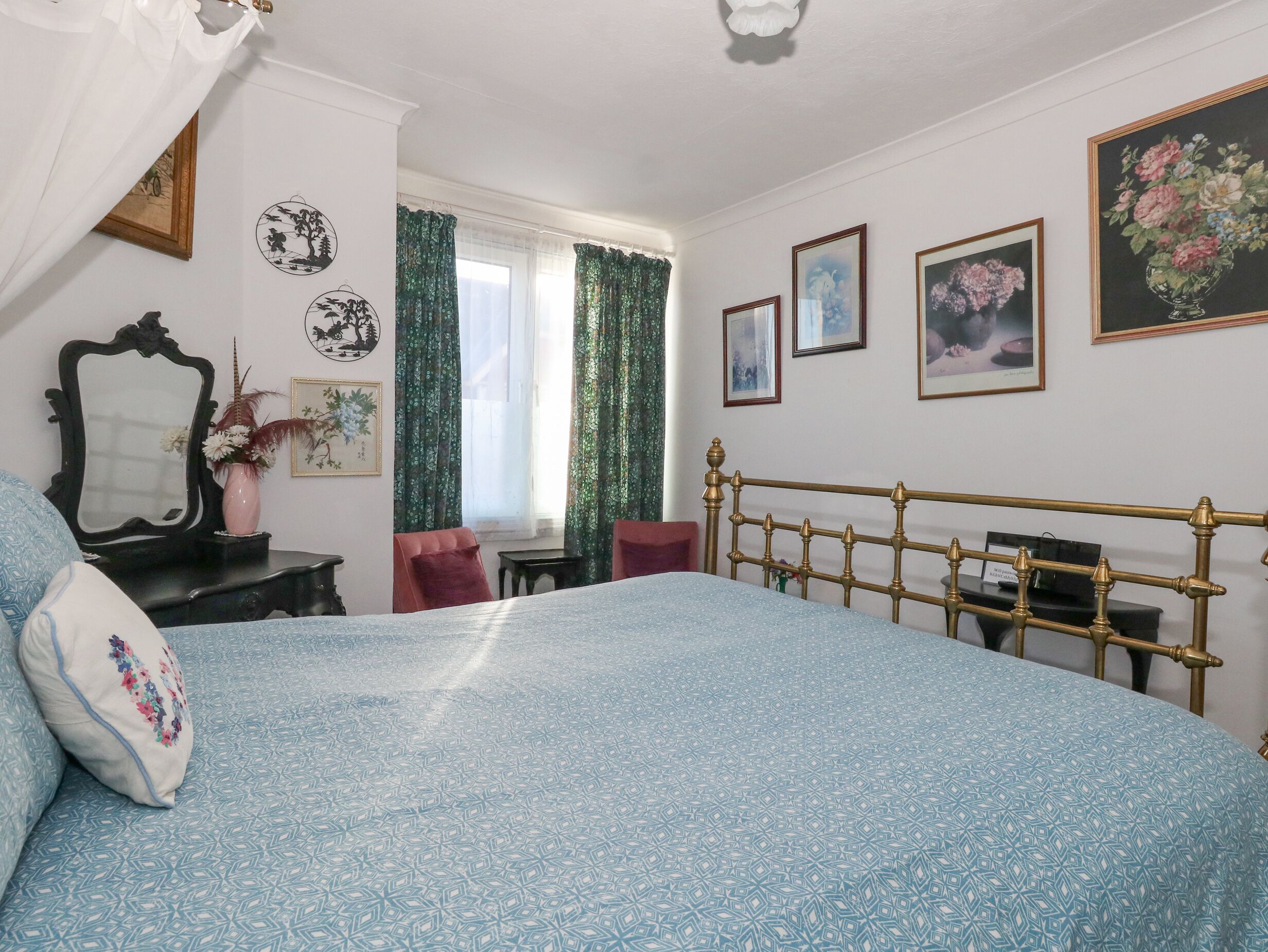 Une chambre à coucher avec une couvre-lit à motifs, un miroir, une commode et un bureau.