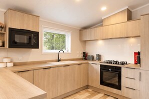 A modern kitchen with wooden cabinets, a built-in microwave, a gas stove, and a dishwasher.