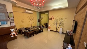 A spacious living room with a sofa set, a coffee table, and decorative elements like wall art and a chandelier. - Secret base B&B (Taitung)