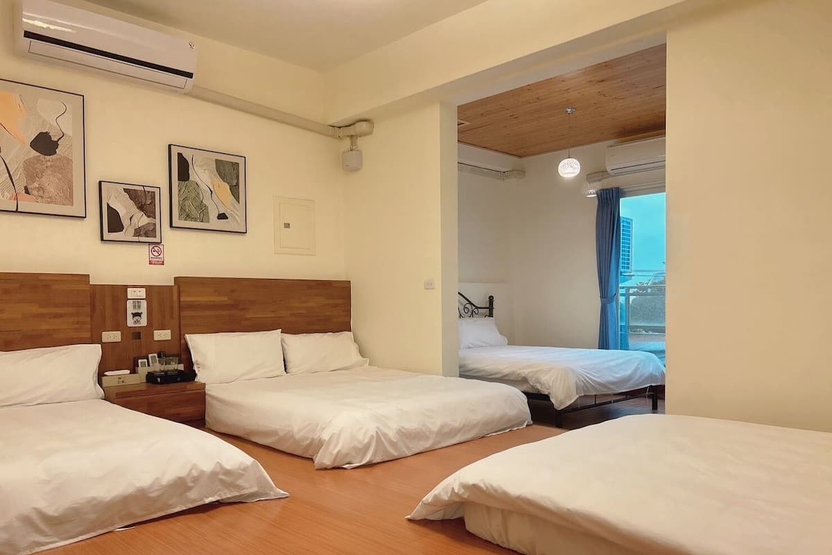 A hotel room with three beds, wooden headboards, and artwork on the walls.