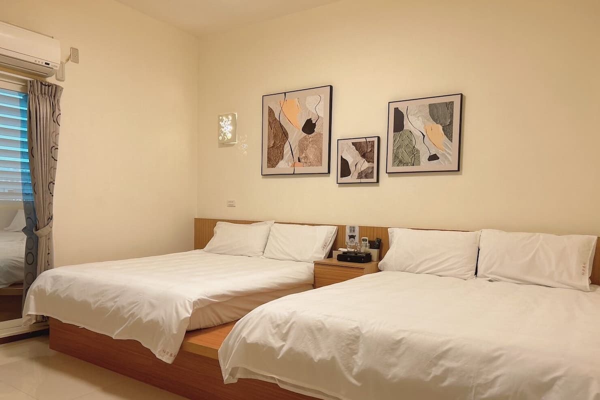 A hotel room with two beds, a nightstand, and artwork on the wall.
