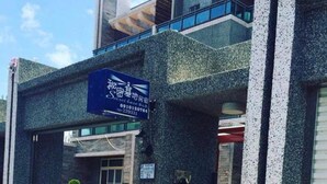 A building with a sign indicating a secret base and a parking area with a black car. - Secret base B&B (Taitung)