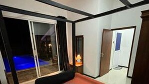 Hotelkamer met een bed, nachtkastje, lamp, een schuifdeur en uitzicht op buiten.