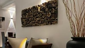 Een moderne woonkamer met een bank, een decoratief kunstwerk en een vaas met takken.
