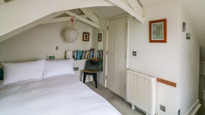 A bedroom with a large bed, a chair, a radiator, and a door.
