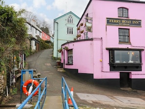 A narrow street leading to a pink building with a sign reading "Ferry Boat Inn Dittisham".