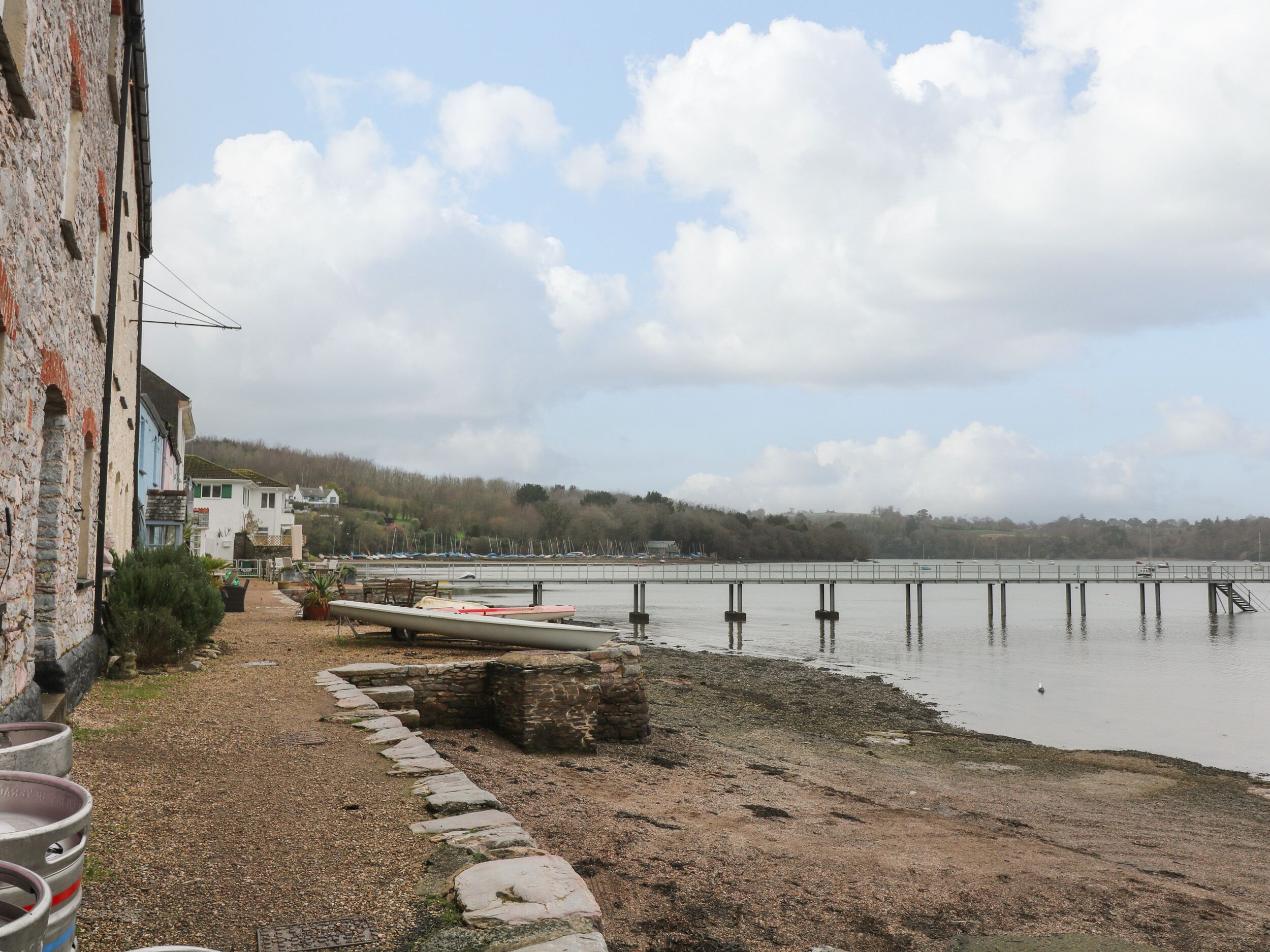 A waterfront property with a stone pathway leading to a dock, boats, and a building with a stone facade.