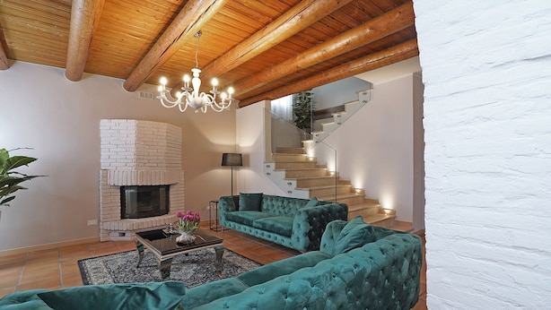 Ein Wohnzimmer mit Kamin, Treppe und einem grünen Sofa.