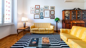 A living room with a checkered rug, two sofas, a lamp, and a wall with framed pictures. - Casa Emme in Rome With 2 Bedrooms and 1 Bathrooms (Rome)