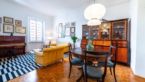 A dining area with a wooden table, chairs, a chandelier, and a piano. - Casa Emme in Rome With 2 Bedrooms and 1 Bathrooms (Rome)