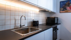 A modern kitchen with a stainless steel sink, a black toaster, and a microwave. - Casa Emme in Rome With 2 Bedrooms and 1 Bathrooms (Rome)