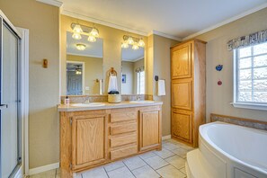 Un baño con muebles de madera, un espejo grande y una bañera.