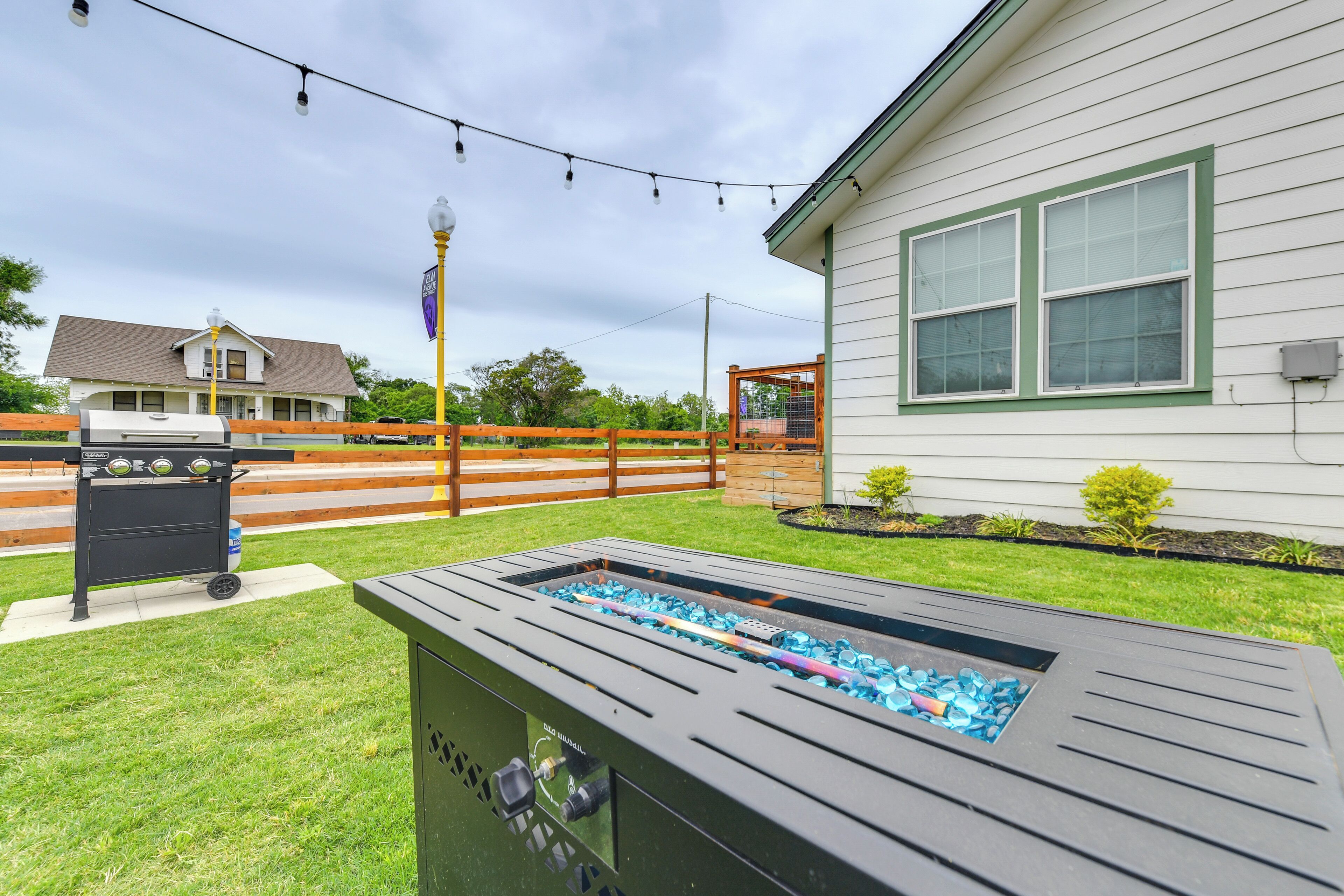 A backyard with a hot tub, a barbecue grill, and a wooden fence.