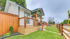 Ein Haus mit Holzterrasse, kleinem Garten und umzäunter Fläche.