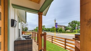 Eine Holzterrasse mit Sitzgelegenheiten im Freien, Blick auf die Straße und einem klaren Himmel.