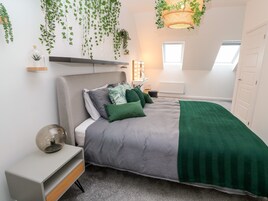 Un dormitorio moderno con cama, mesita de noche y una planta colgante.