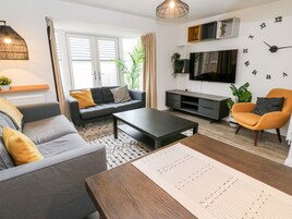 Una sala de estar moderna con un sofá, sillones, una mesa de centro y un televisor.