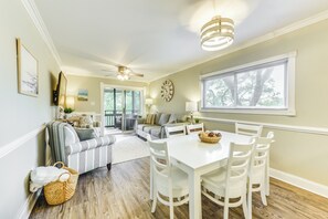 A dining area with a white table and chairs, a ceiling fan, and a window with blinds. - Walk to Ocean: Unit w/ 2 Balconies in Myrtle Beach (Myrtle Beach)