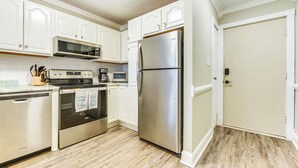 A kitchen with white cabinets, stainless steel appliances, and a wooden floor.