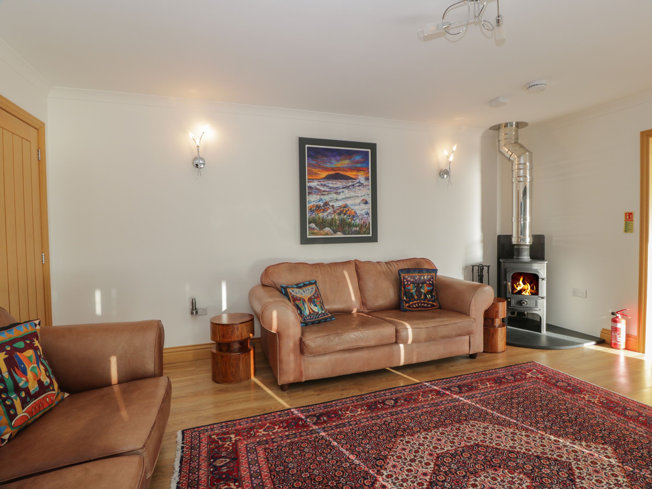 A living room with a sofa, a rug, a fireplace, and a painting on the wall.