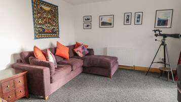 A modern living room with a sectional sofa, a telescope, and framed artwork on the walls.
