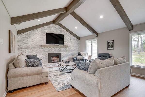 A living room with a fireplace, two sofas, a coffee table, and a TV mounted on the wall.